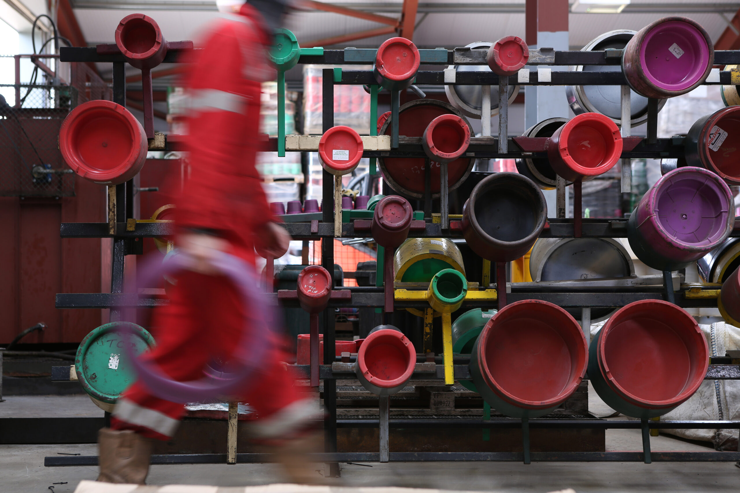 An employee of Norkram Ltd based in Peterhead walks past a rack of thread protectors testers holding a bumper ring made from recyclable plastics for the oil and gas industry